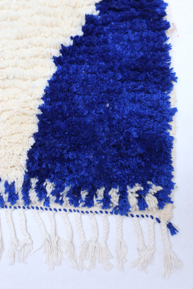 Tapis berbère en laine au design moderne, dominé par des motifs géométriques bleus et crème avec des franges détaillées.