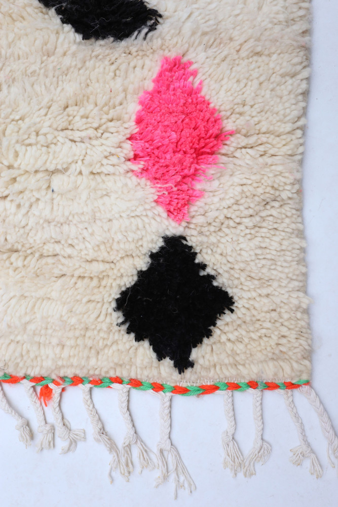 Tapis berbère avec motifs géométriques en rose fluo, noir et crème, au style artisanal et chaleureux.