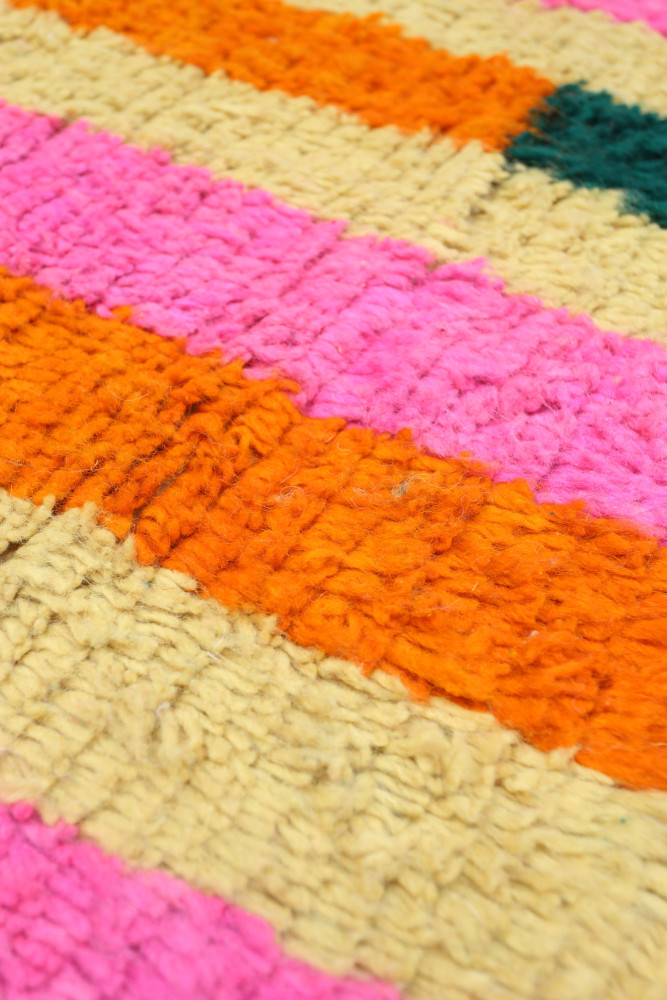 Tapis berbère coloré avec des rayures rose, orange et vert, offrant un style moderne et chaleureux.