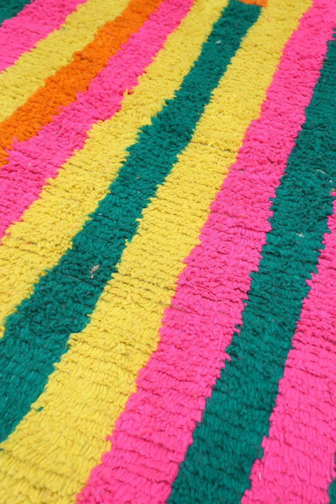 Tapis berbère aux rayures colorées en rose, vert, orangé et jaune, offrant un style contemporain et vibrant.
