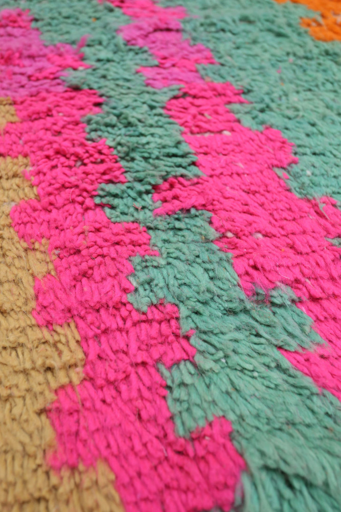 Tapis berbère aux couleurs vives avec des motifs géométriques en rose, vert et orange, ajoutant une touche d\'authenticité moder