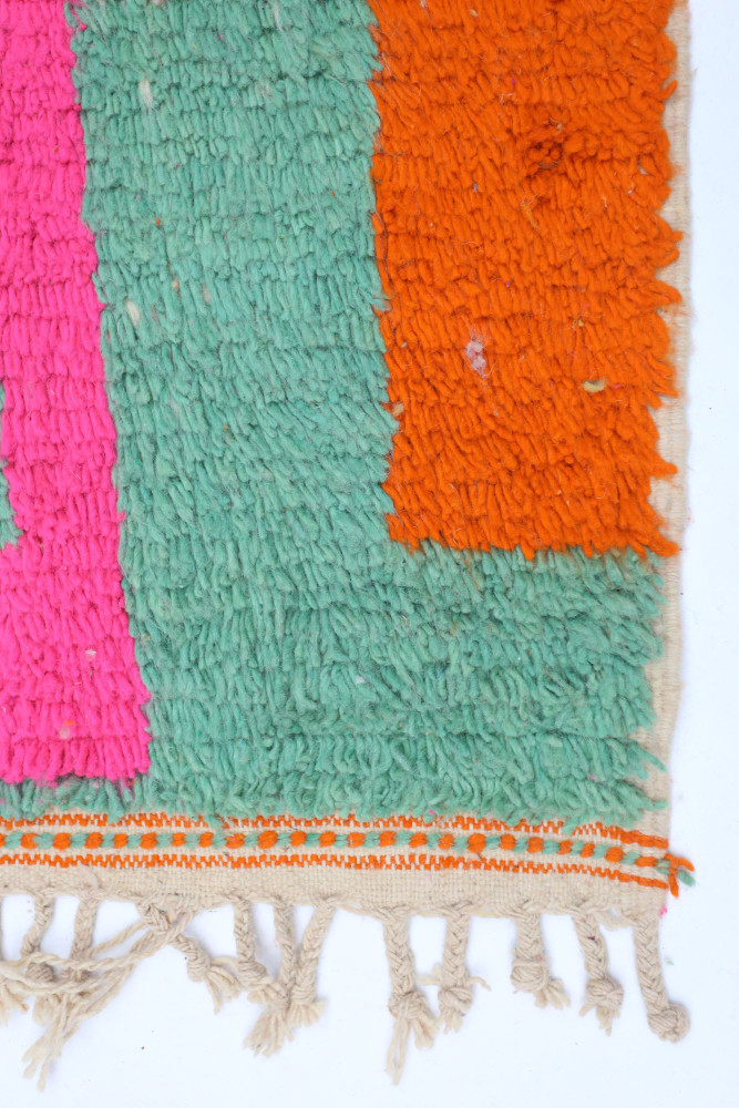 Tapis berbère coloré avec des motifs en vert, orange et rose, ajoutant une touche contemporaine à votre décoration intérieure.