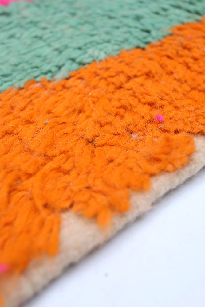 Tapis berbère coloré avec des motifs texturés en orange et vert, ajoutant une touche moderne et vibrante à votre intérieur.