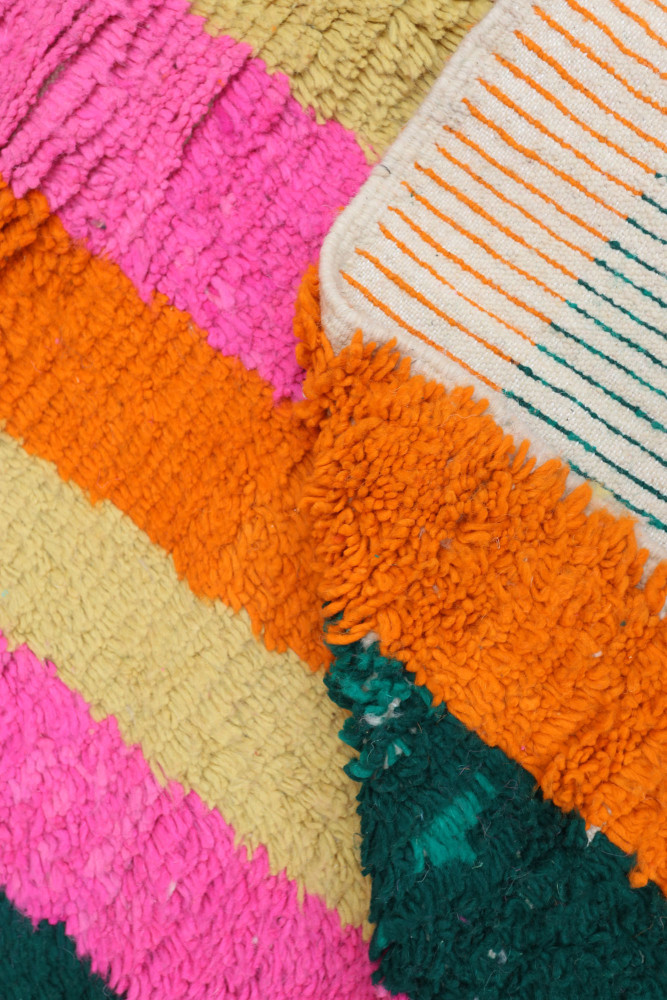 Tapis berbère coloré avec des rayures vives en rose, orange, et vert, offrant un style moderne et joyeux.