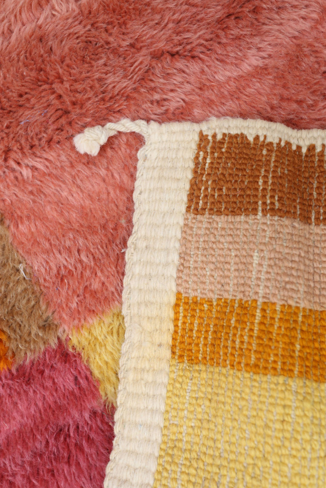 Tapis berbère à motifs géométriques aux teintes rose, jaune et beige, offrant une ambiance chaleureuse et moderne.