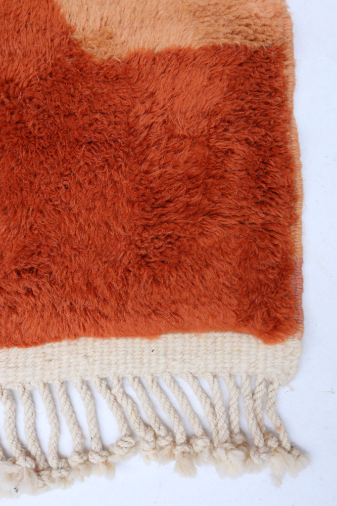 Tapis berbère aux teintes orange et beige, avec des motifs doux et modernes, ajoutant une touche élégante à votre intérieur.