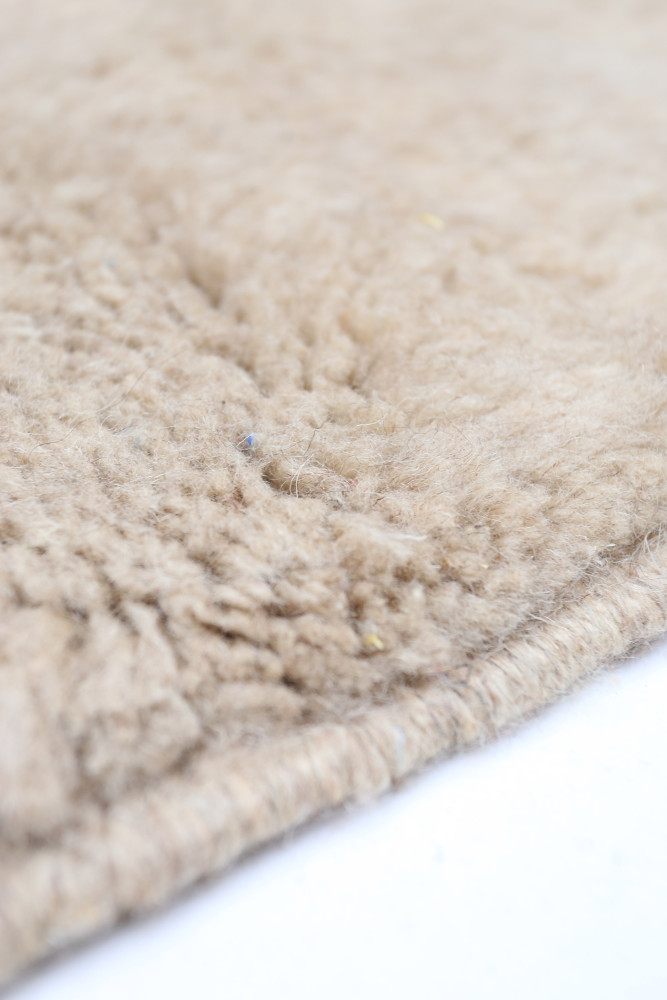 Tapis berbère beige doux au toucher avec des motifs naturels et une texture riche.