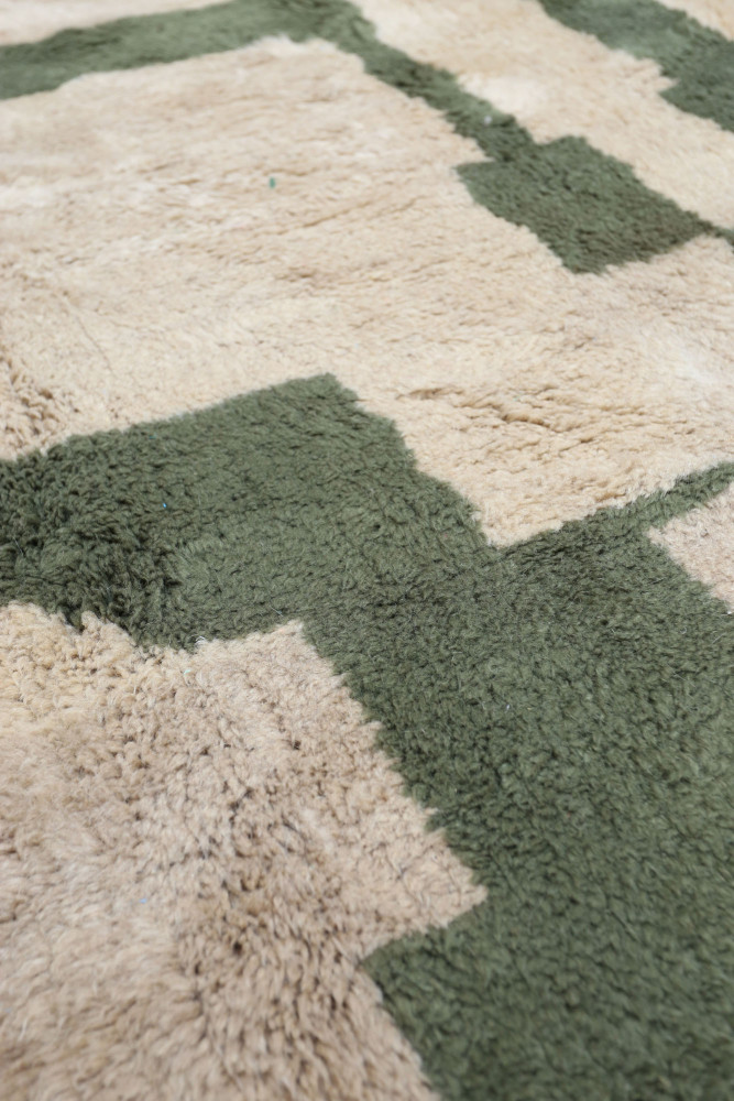Tapis berbère au design géométrique avec des teintes beiges et vertes, offrant une texture douce et chaleureuse.