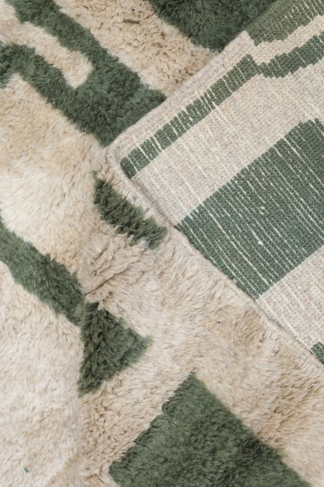 Tapis berbère en laine avec des motifs géométriques, aux couleurs beige et vert olive, pour un intérieur contemporain.