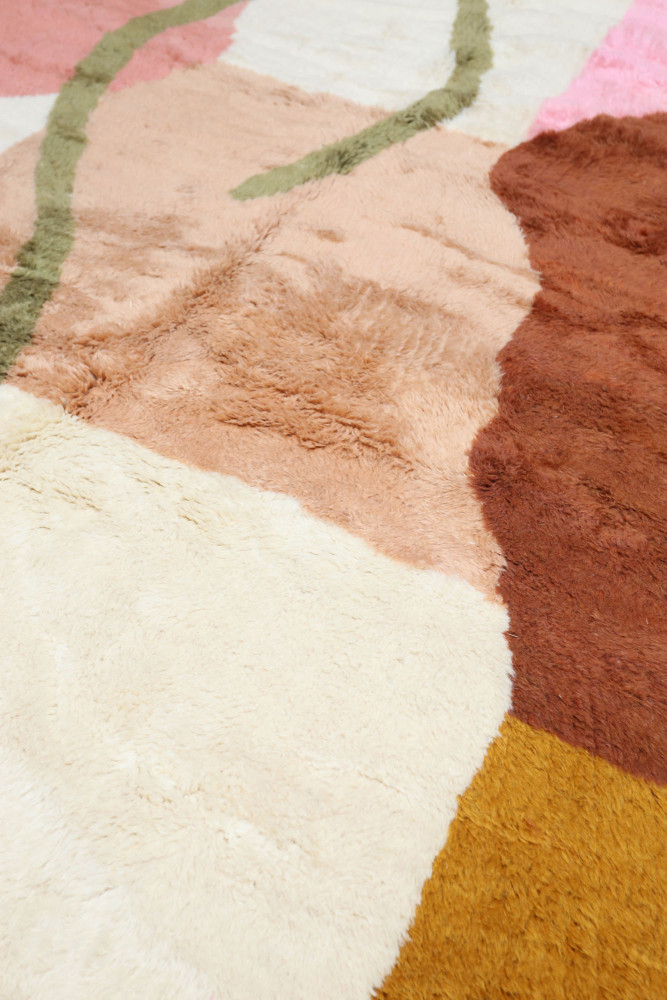Tapis berbère aux couleurs chaudes, motifs géométriques modernes en rose, beige, marron et jaune.