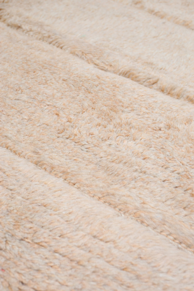 Tapis berbère aux tons beiges, avec un motif texturé et doux pour une ambiance chaleureuse et accueillante.