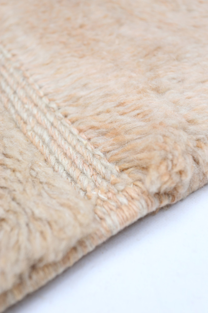 Tapis berbère en tons beiges doux avec des motifs subtils et une texture moelleuse et accueillante.