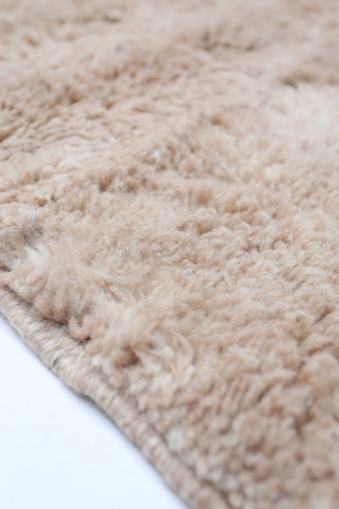 Tapis berbère en laine douce, de couleur beige, avec un motif texturé et accueillant, idéal pour un intérieur chaleureux.