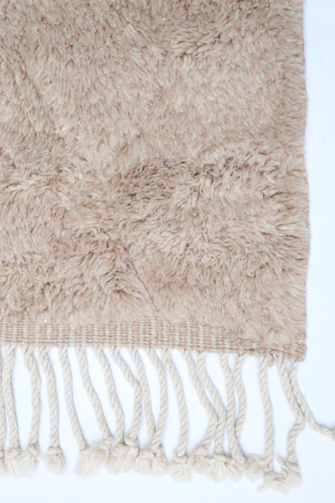 Tapis berbère en laine beige, au style naturel, avec une texture douce et des franges élégantes.