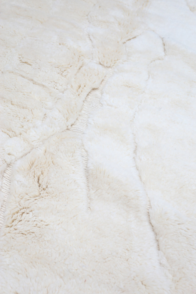 Tapis berbère en laine, blanc crémeux avec motifs texturés, offrant une touche traditionnelle et chaleureuse à votre intérieur.