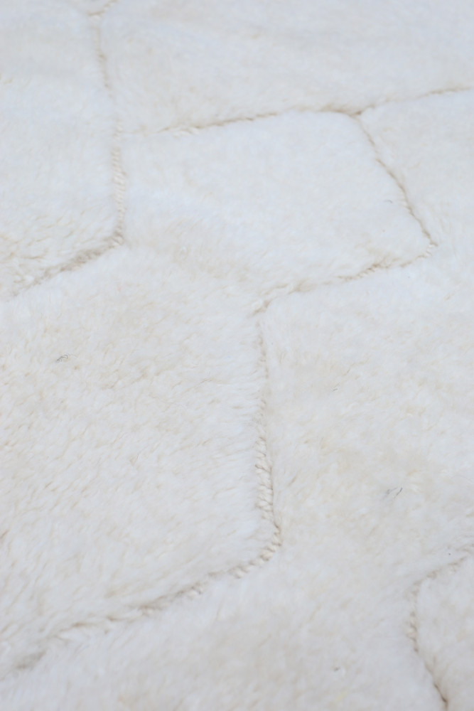 Tapis berbère en laine blanche aux motifs géométriques hexagonaux offrant une texture douce et chaleureuse.