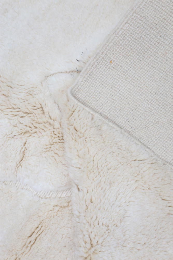 Tapis berbère en laine douce, couleur crème, au design texturé et minimaliste, apportant chaleur et confort.