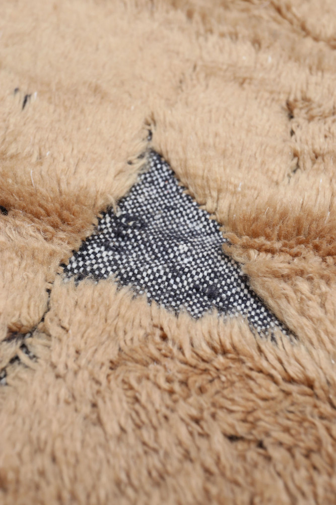Tapis berbère beige avec motifs noirs et texture douce, idéal pour une décoration intérieure chaleureuse.