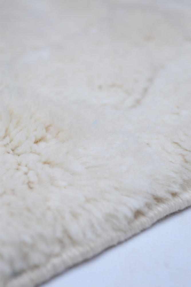 Tapis berbère en laine beige, au style minimaliste et aux textures douces, parfait pour un intérieur chaleureux.