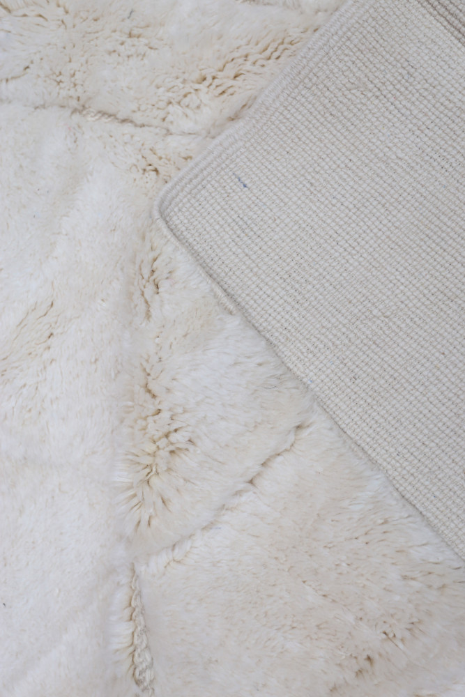 Tapis berbère moelleux blanc avec des motifs géométriques subtils, parfait pour un intérieur contemporain.