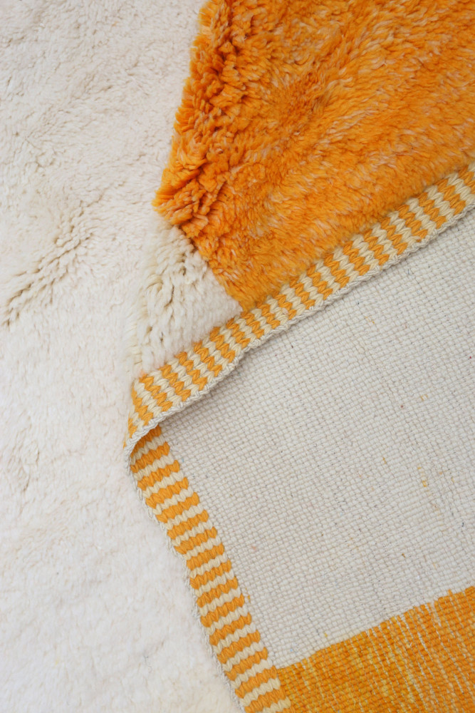 Tapis berbère aux teintes blanches et orange avec des motifs rayés modernes et doux au toucher.