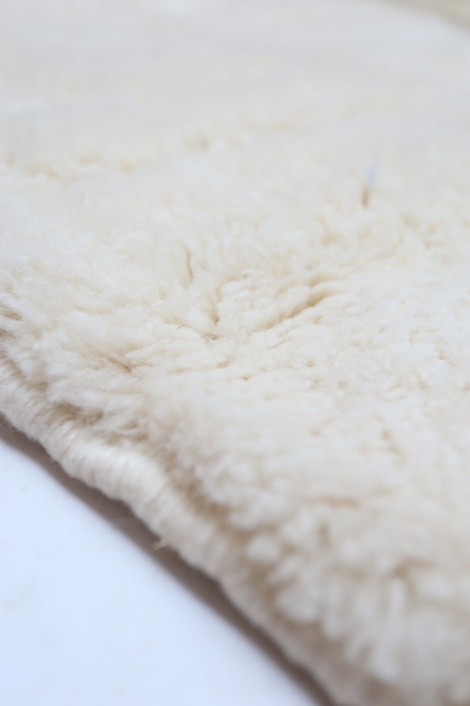 Tapis berbère en laine douce avec une teinte ivoire et un aspect shaggy texturé, idéal pour un intérieur chaleureux.