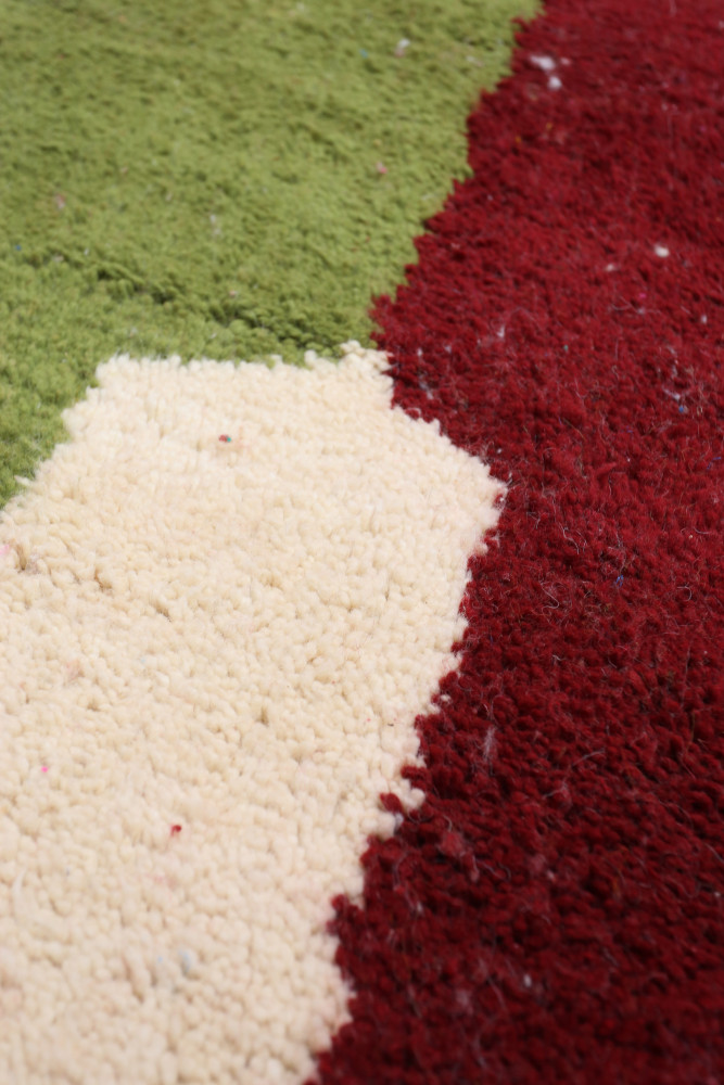 Tapis berbère coloré avec des motifs géométriques en rouge, vert et crème, offrant une touche artisanale moderne.