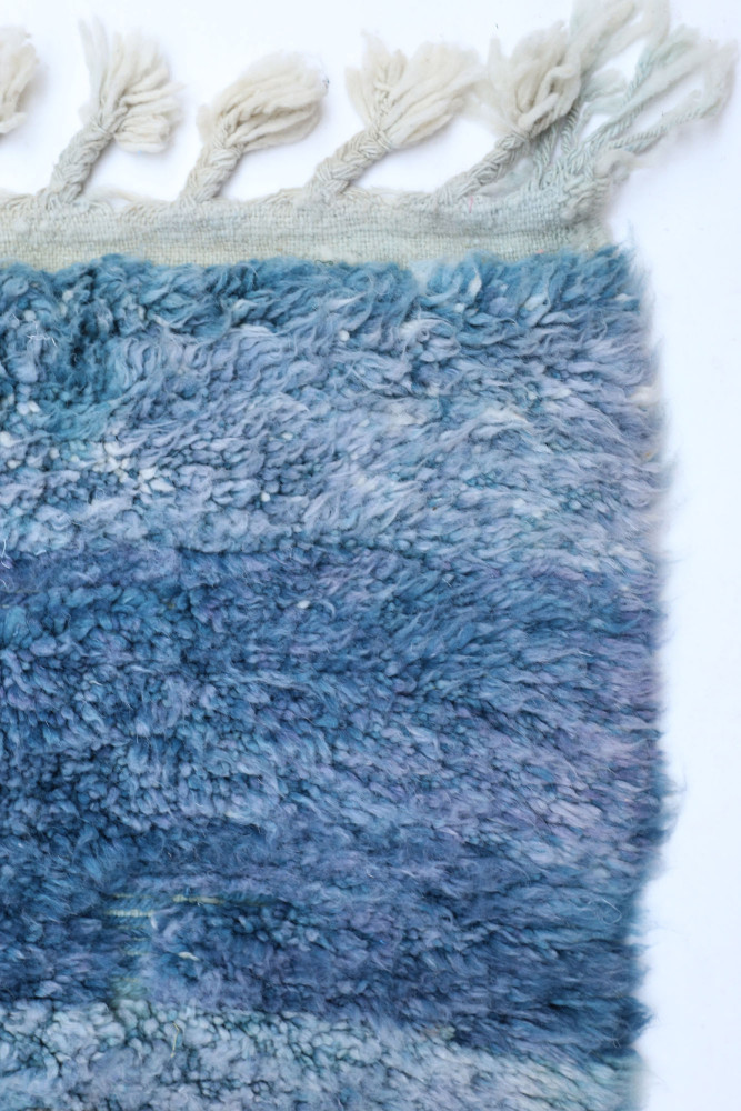 Tapis berbère aux tons bleus dégradés, avec une texture douce et des franges délicates, alliant tradition et modernité.