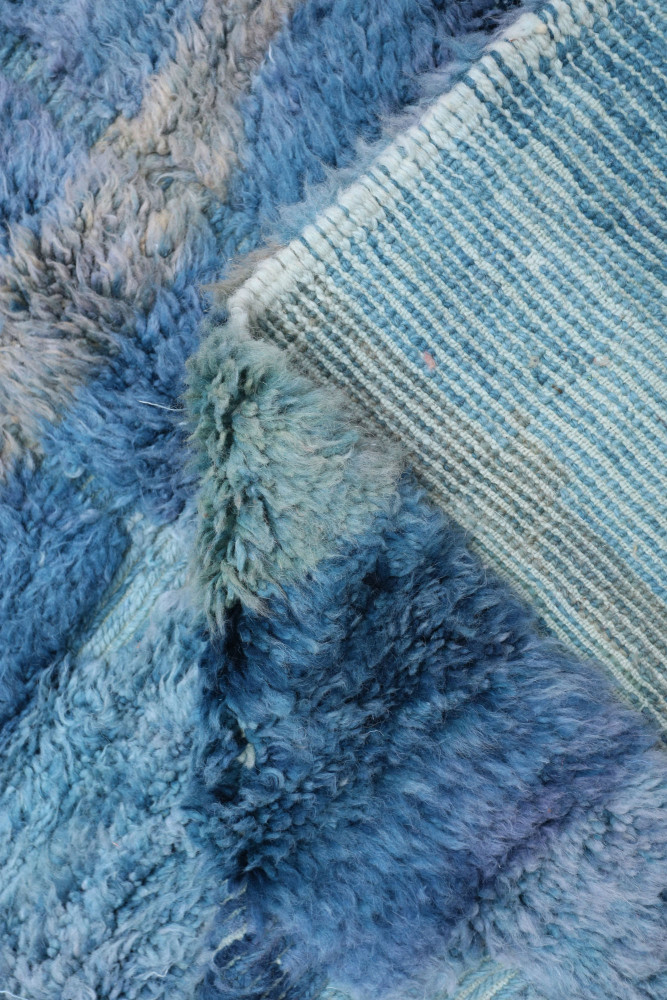 Tapis berbère aux nuances de bleu, avec des motifs texturés et une beauté artisanale unique.