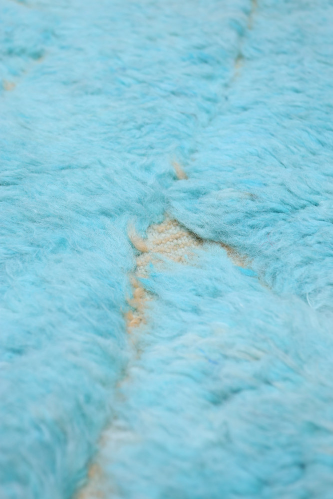 Tapis berbère doux en bleu clair avec motifs géométriques sur un fond beige, ajoutant une touche contemporaine à votre décor.
