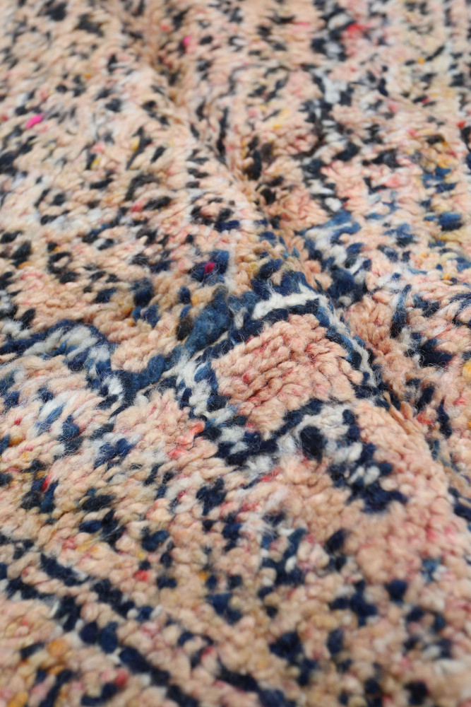 Tapis berbère aux motifs géométriques en rose, bleu marine et beige, ajoutant une touche artisanale à votre intérieur.