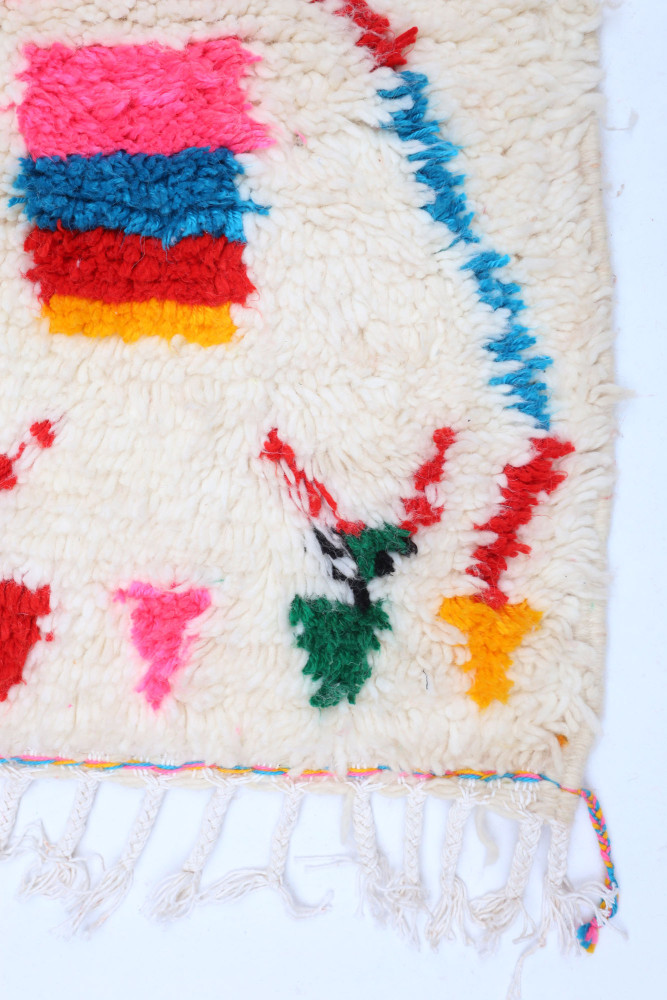 Tapis berbère aux couleurs vives avec des motifs géométriques sur fond crème.
