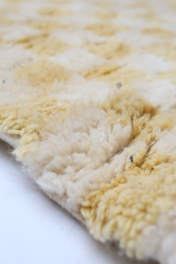 Tapis berbère aux motifs géométriques en jaune et crème, offrant une texture douce et chaleureuse.