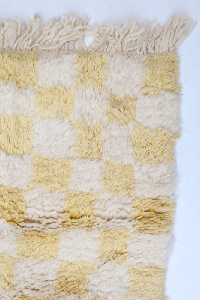 Tapis berbère à motifs carrés en jaune et crème, offrant une texture douce et chaleureuse pour une décoration confortable.