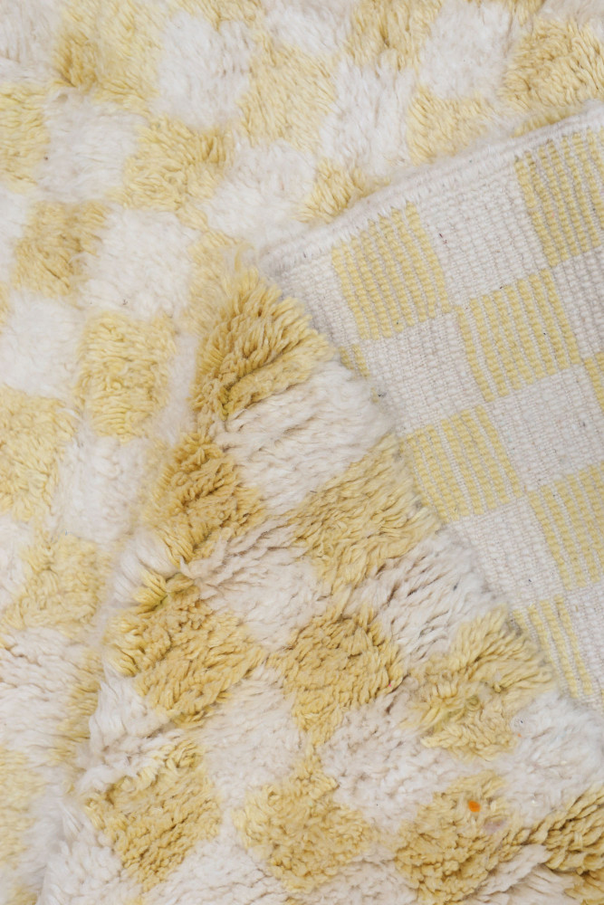 Tapis berbère à motifs à carreaux en jaune et blanc, offrant une texture douce et moderne pour la décoration intérieure.
