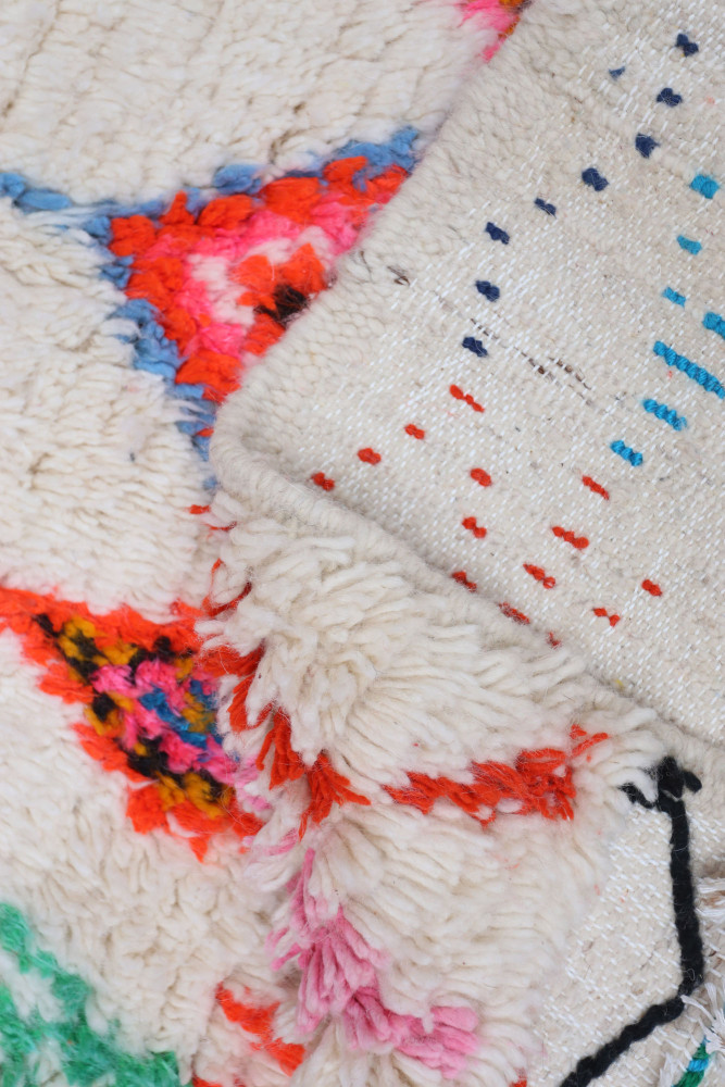 Tapis berbère coloré avec des motifs géométriques vifs sur un fond clair.