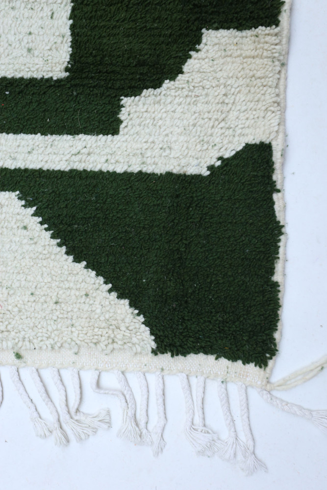 Tapis berbère en laine avec des motifs géométriques en vert et crème, parfait pour ajouter du style à votre intérieur.