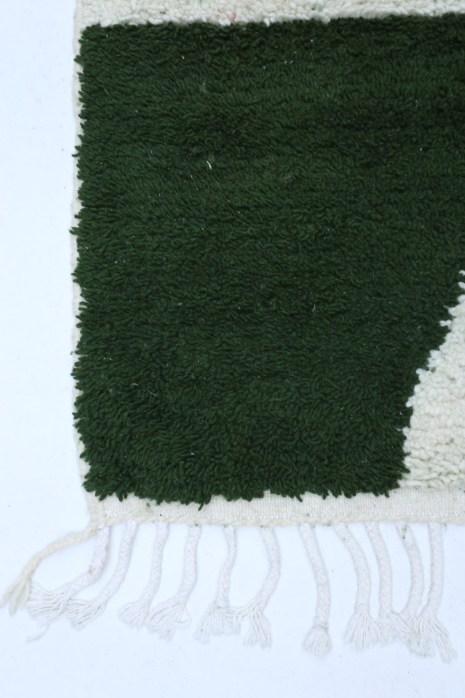 Tapis berbère en laine douce, avec des motifs géométriques en vert et blanc, ajoutant une touche artisanale à votre intérieur.