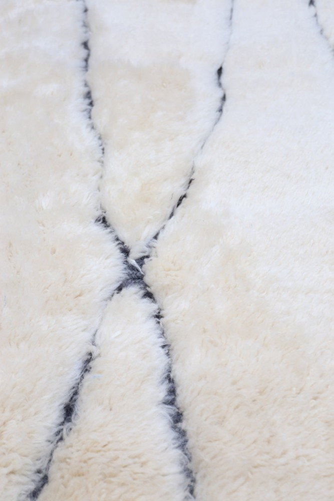 Tapis berbère en fausse fourrure blanche avec des motifs en lignes noires, idéal pour un décor moderne et chaleureux.