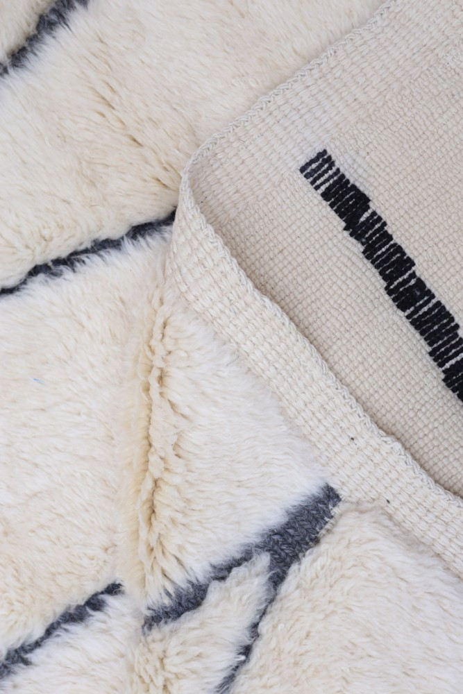 Tapis berbère en laine crémeux avec motifs géométriques en noir, ajoutant une touche naturelle et moderne à votre intérieur.