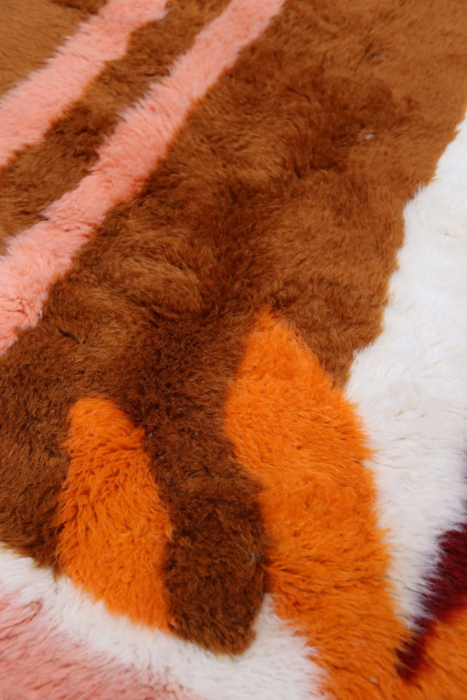 Tapis berbère aux motifs géométriques, couleurs brunes, orange, rose et blanche, apportant chaleur et authenticité à votre décor