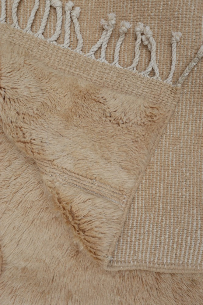 Tapis berbère en beige, au style doux, avec un motif texturé et des franges élégantes.