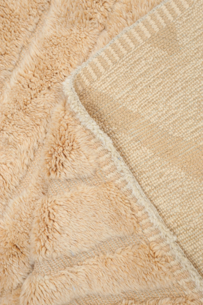 Tapis berbère à motifs géométriques en beige et crème, avec une texture moelleuse et chaleureuse.
