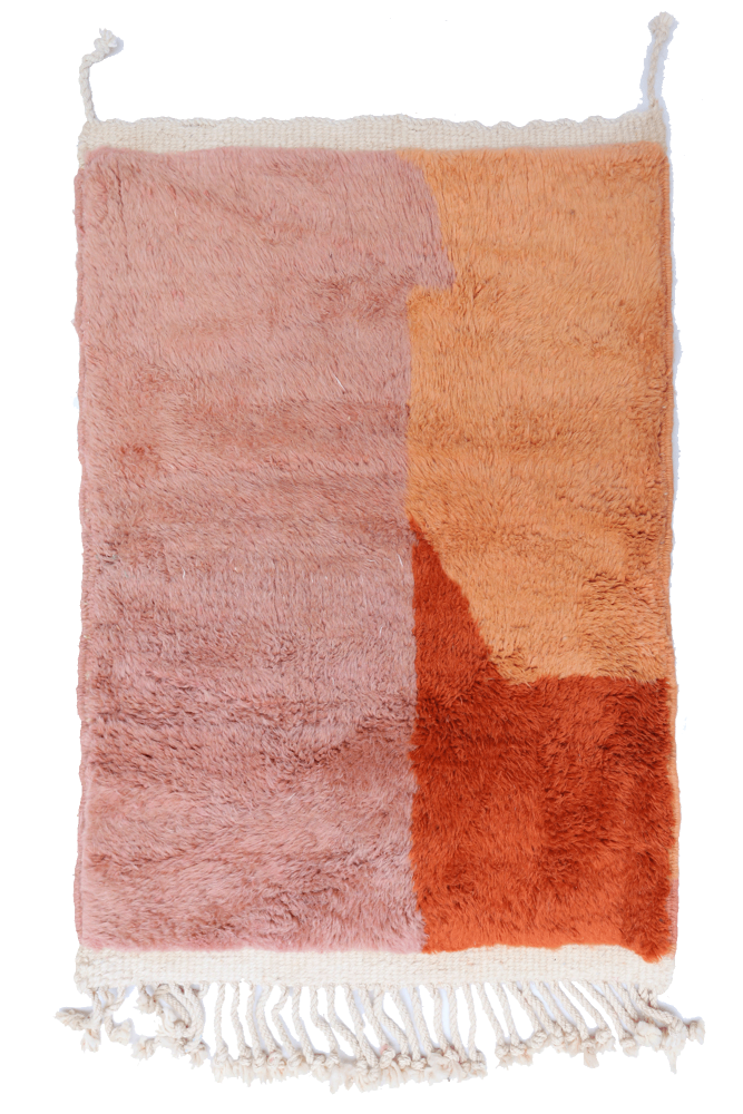Tapis berbère aux teintes douces de rose, orange et terre cuite avec un design géométrique moderne et des franges.