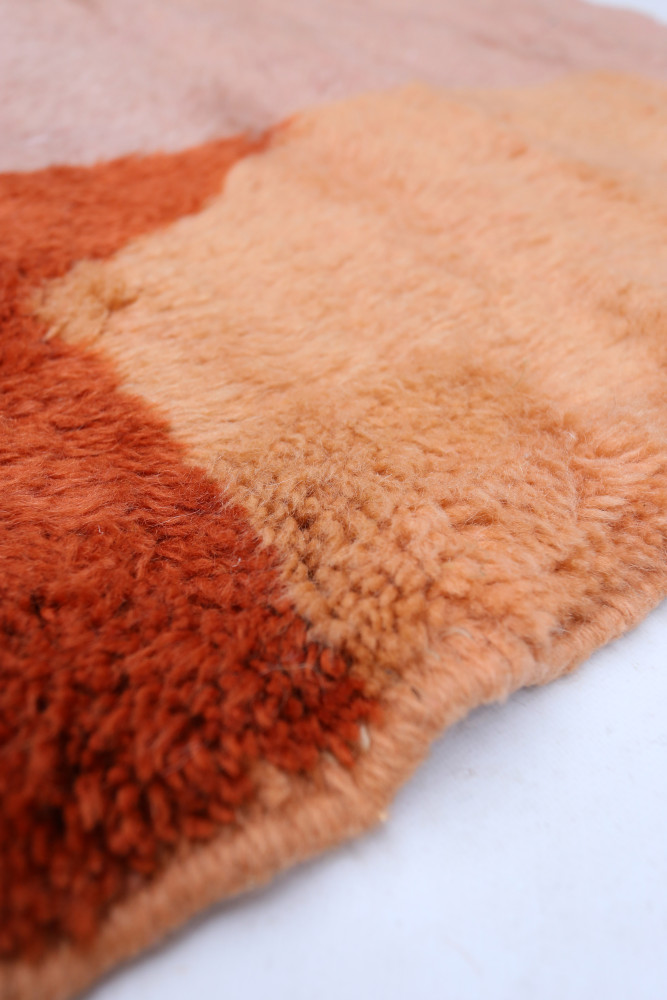 Tapis berbère au style chaleureux, avec des teintes orange et beige et des motifs doux en texture.
