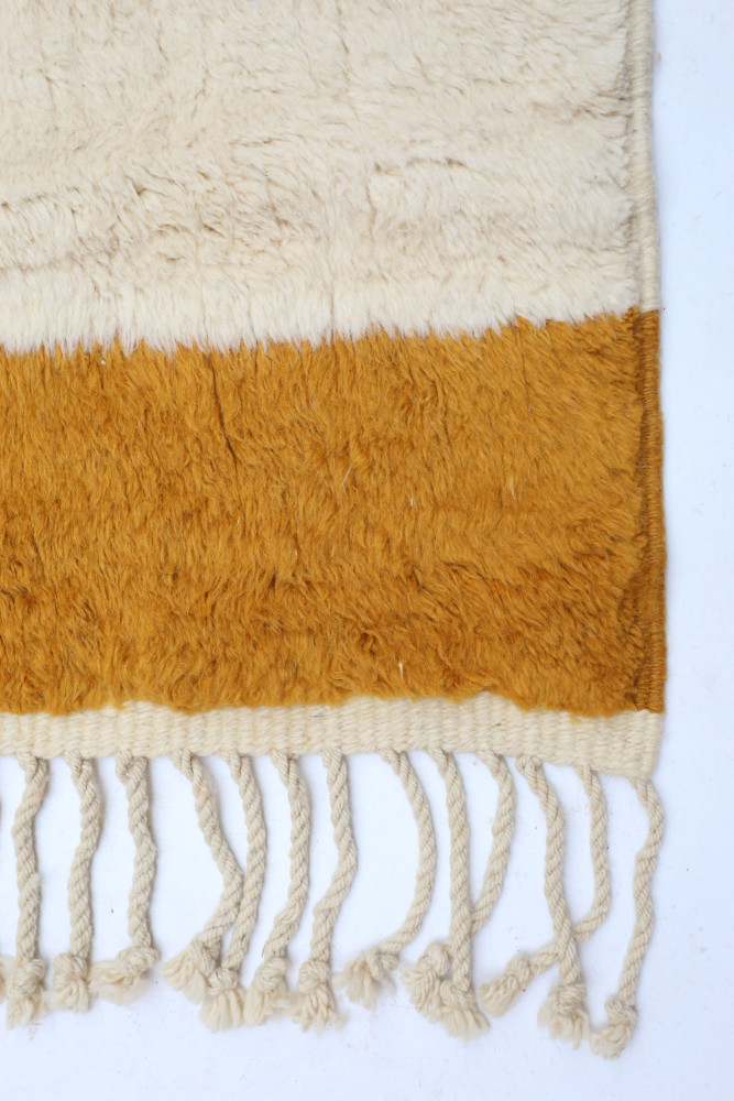 Tapis berbère en laine beige et orange, avec un design sobre et des franges délicates apportant chaleur et authenticité.
