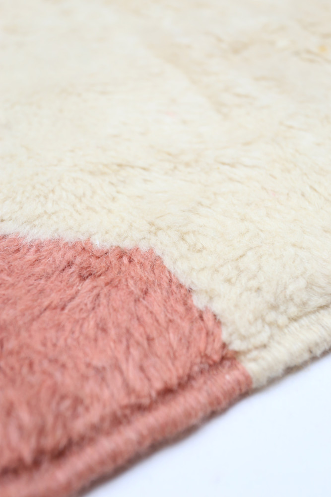 Tapis berbère à la texture douce, aux teintes crème et rose avec des motifs minimalistes élégants.