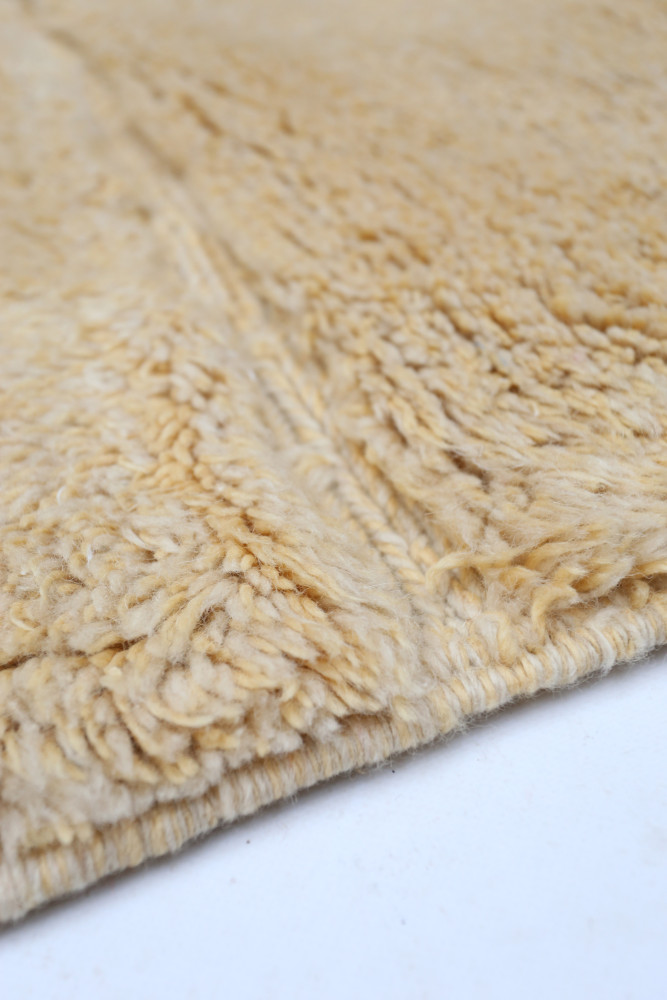 Tapis berbère en laine beige, au design doux et texturé, parfait pour ajouter chaleur et style à tout intérieur.