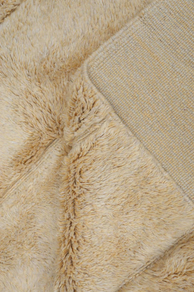 Tapis berbère douillet en teintes beige et crème avec motifs texturés et doux, idéal pour un intérieur chaleureux.