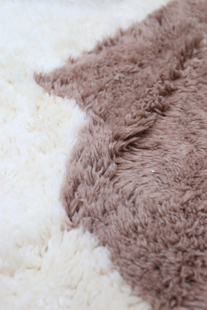 Tapis berbère aux teintes crémeuses et marron, avec un motif doux et texturé, idéal pour un intérieur chaleureux.